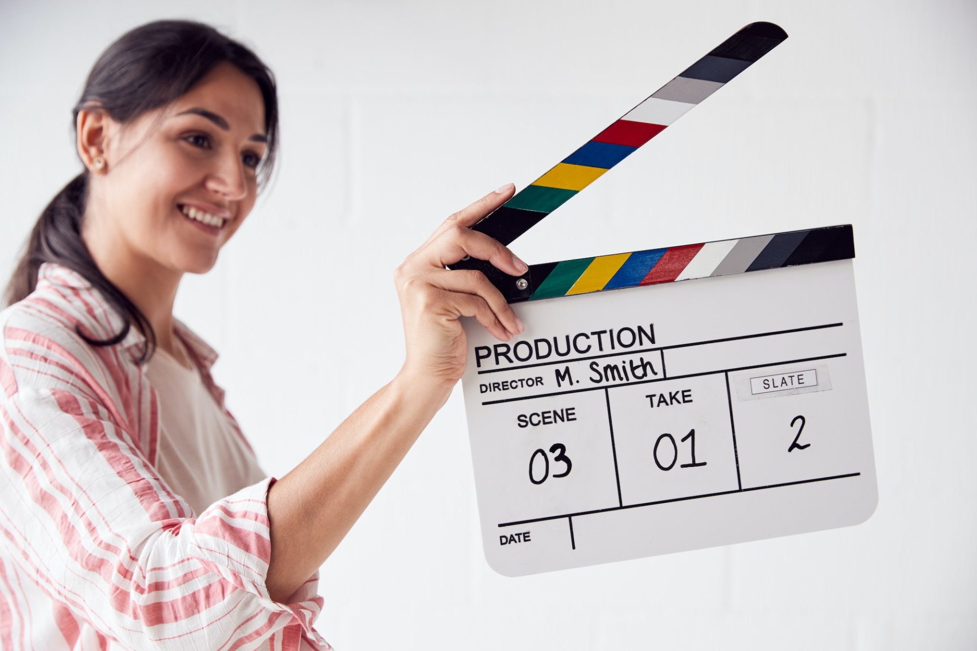 Female Videographer Holding Clapper Board On Video Film Production In White Studio