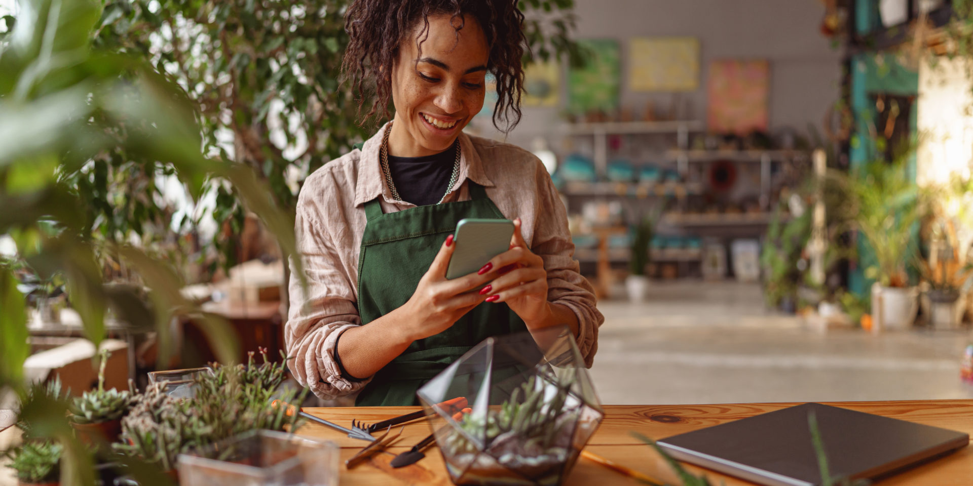 Smiling woman florist taking picture with her plants for publishing in social media